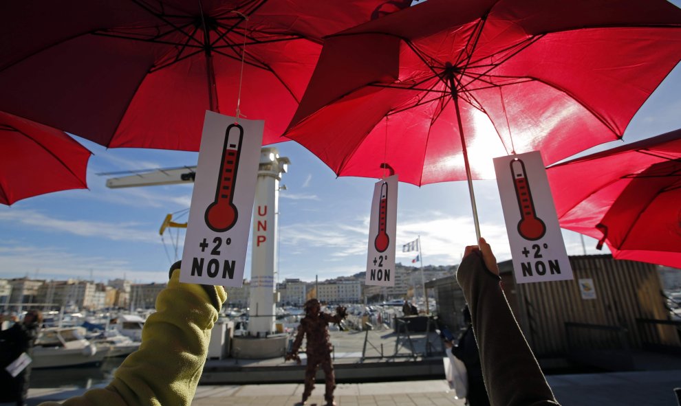 Los activistas ecologistas sujetan sombrillas de color rojo, ya que participan en una reunión simbólica, una cadena humana, después de la cancelación de una marcha climático en la capital francesa. Marsella, Francia. REUTERS / Jean-Paul Pelissier