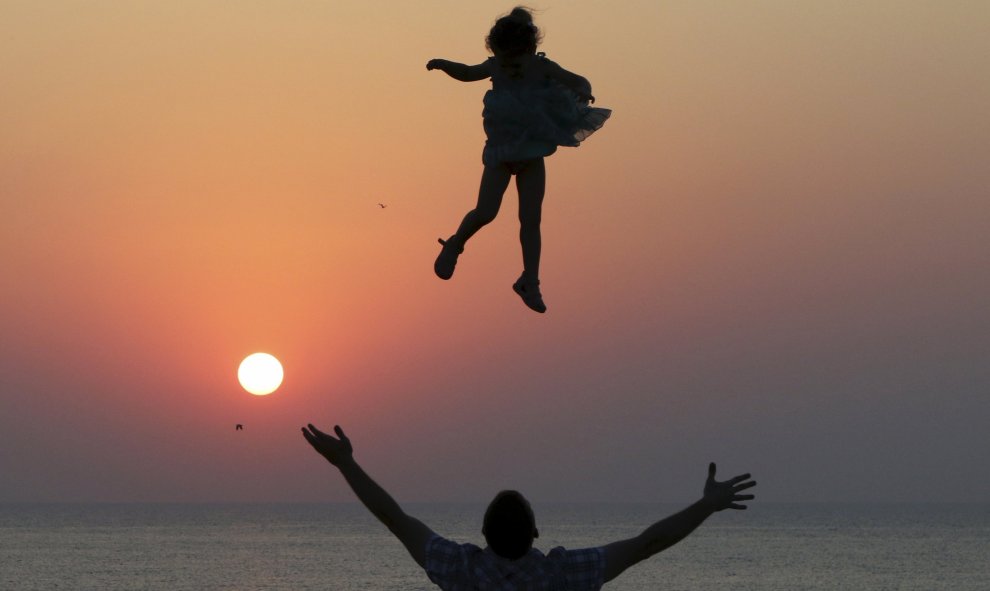 Un hombre lanza a una niña al aire al atardecer, en el puerto del Mar Negro de Sebastopol, en Crimea, Ucrania.  REUTERS/Pavel Rebrov