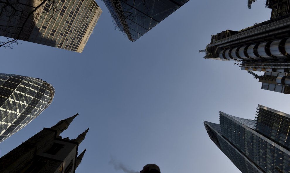 Un trabajador de la ciudad camina por las calles de Londres al lado de la iglesia St. Mary Axe rodeado de rascacielos en la zona de negocios. REUTERS / Toby Melville