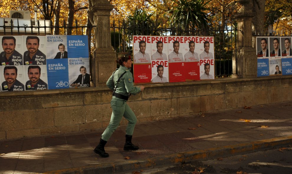 Una legionaria corre junto a una valla con carteler de los diferentes candidatos de las elecciones del 20-D, en Ronda, cerca de Málaga. REUTERS/Jon Nazca