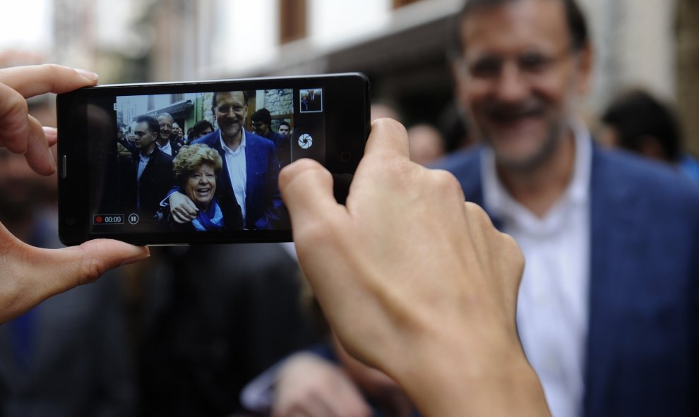 Mariano Rajoy se hace una foto con una simpatizante durante un paseo del candidato del PP por la localidad asturiana de Cangas de Onis. REUTERS/Eloy Alonso