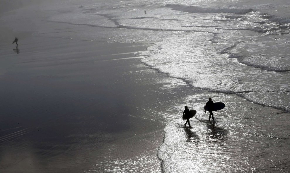 Unos surfistas se dirigen al mar para practicar una sesión de entrenamiento en este inusual cálido invierno francés. REUTERS/Regis Duvignau