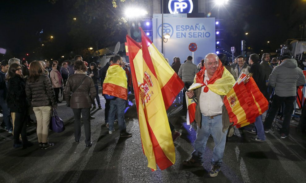 Algunos simpatizantes junto a la sede del Partido Popular, en la madrileña calle de Génova, siguiendo esta noche los primeros resultados electorales. EFE/Chema Moya