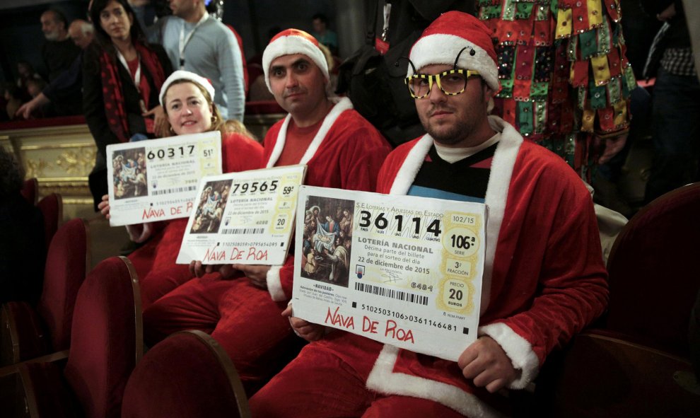 Tres personas disfrazadas de Papá Noel presencian el Sorteo de Navidad. REUTERS/Andrea Comas