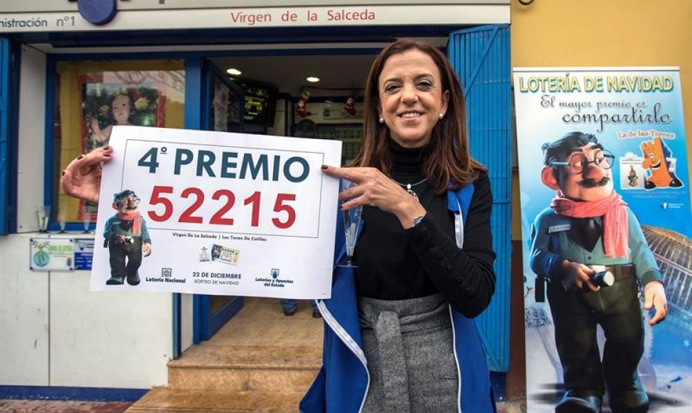 La propietaria de la administración número uno de las Torres de Cotillas (Murcia), muestra el cartel con el cuarto premio. EFE/Marcial Guillén