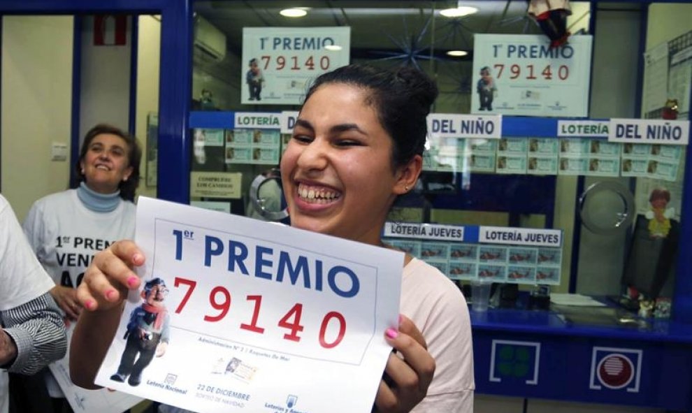 Una joven sonríe con una copia del número 79.140, agraciado con el Gordo de Navidad. EFE /Carlos Barba