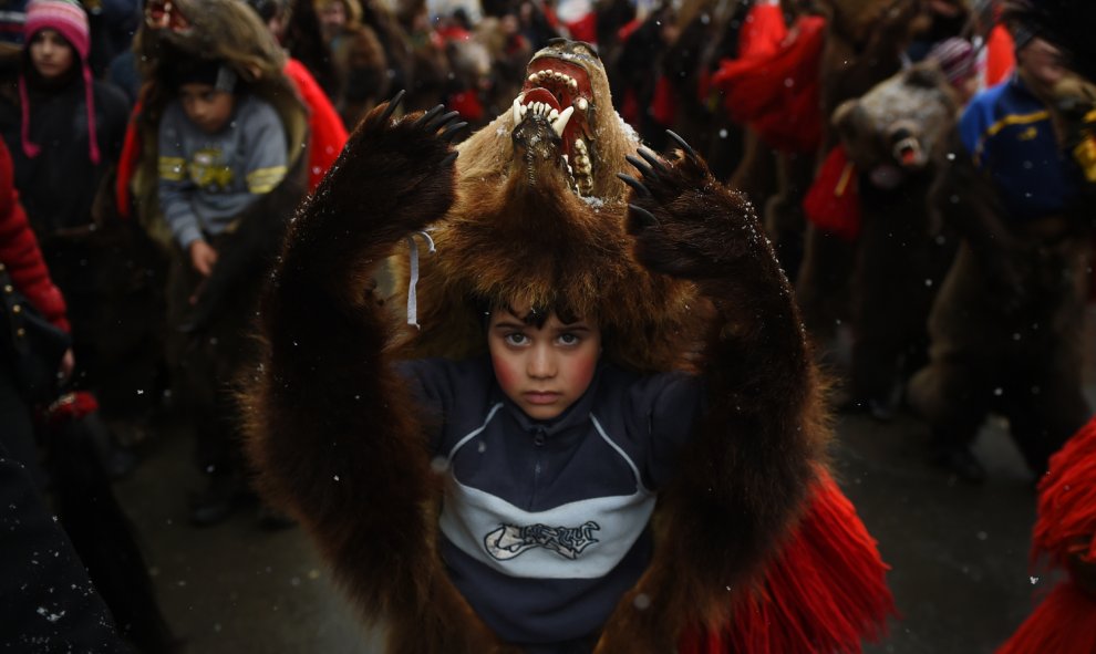 Un niño vestido con la piel de un oso se pasea por las calles de la ciudad Comanesti, en Rumanía, el 30 de diciembre 2015 durante un desfile para ahuyentar a los malos espíritus del pasado año. DANIEL MIHAILESCU / AFP