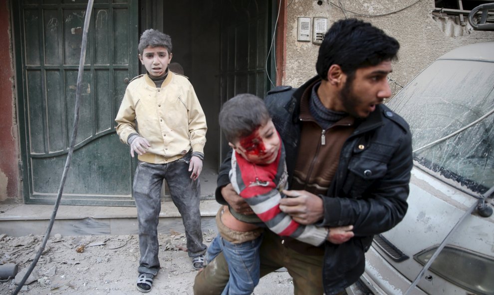 Un hombre saca a un niño herido  de un edificio dañado de los ataques de las fuerzas leales al presidente Bashar al-Assad según denuncian los activistas de la zona en Douma, al este de Ghouta en Damasco, Siria 30 de diciembre de 2015. REUTERS / Bassam Kha