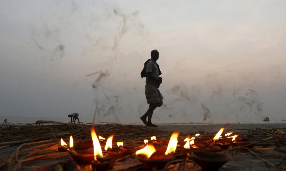Un peregrino hindú camina junto a una hilera de lámparas encendidas después de tomar un baño sagrado en la confluencia de los ríos Ganges y la Bahía de Bengala en Sagar Island. REUTERS/Rupak De Chowdhuri