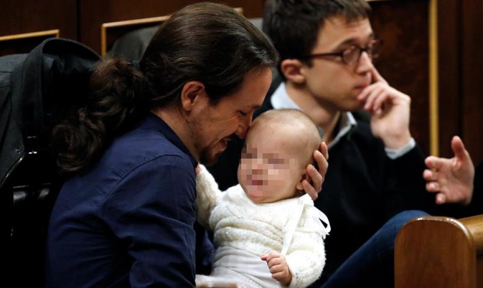 El líder de Podemos, Pablo Iglesias, con la hija de la diputada de su partido Carolina Bescansa en sus brazos en su escaño del Congreso.- EFE