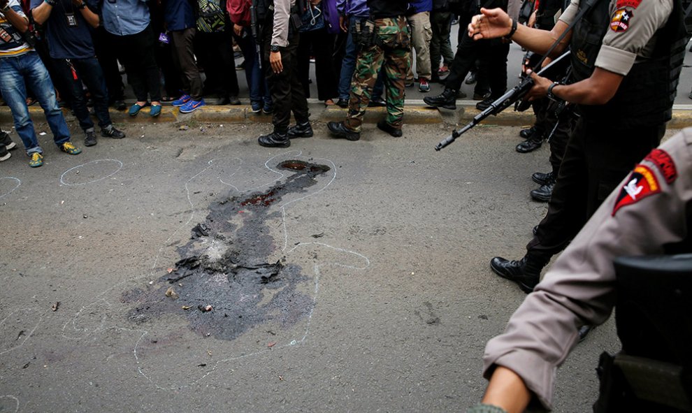 Policías indonesios, junto a la silueta de un cadáver, en el distrito financiero de Thamrin en Yakarta, tras el asalto de un grupo de hombres armados en el centro de la capital indonesia. Los terroristas del Estado Islámico habían amenazado al país con po