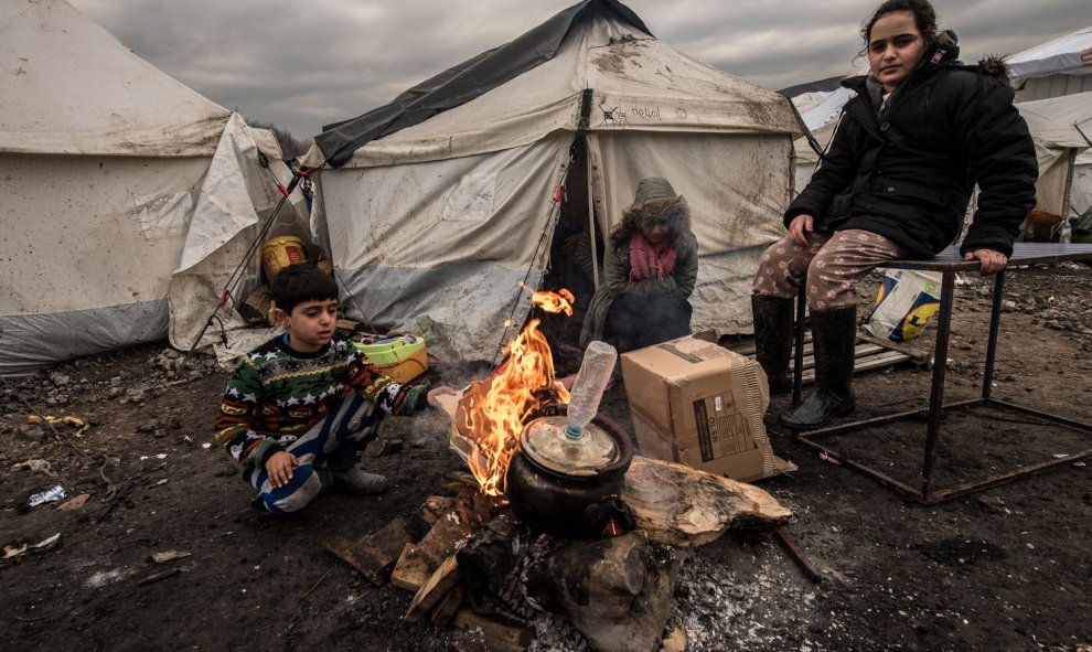 Varios inmigrantes intentan entrar en calor con un brasero en el campamento cerca de Dunkerque, donde viven alrededor de 2.500 de refugiados./AFP