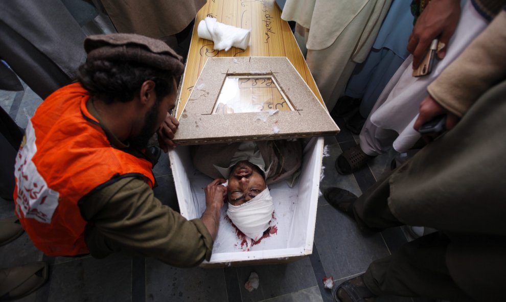 Un operario limpia el cuerpo sin vida de una las víctimas del ataque a la Universidad Bacha Khan de Charsadda, Pakistán, el 20 de enero del 2016. Cuatro terroristas atacaron el campus asesinando al menos a 21 personas, entre ellas estudiantes, profesores