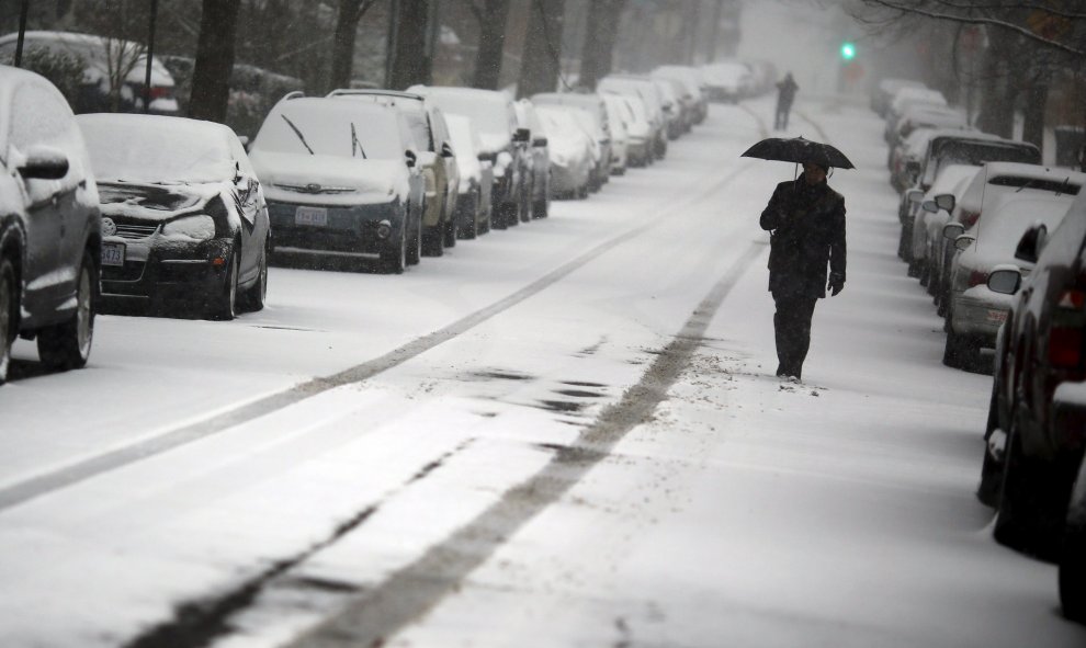 Un hombre con paraguas camina bajo el manto blanco que cubre las calles de Washington. /REUTERS