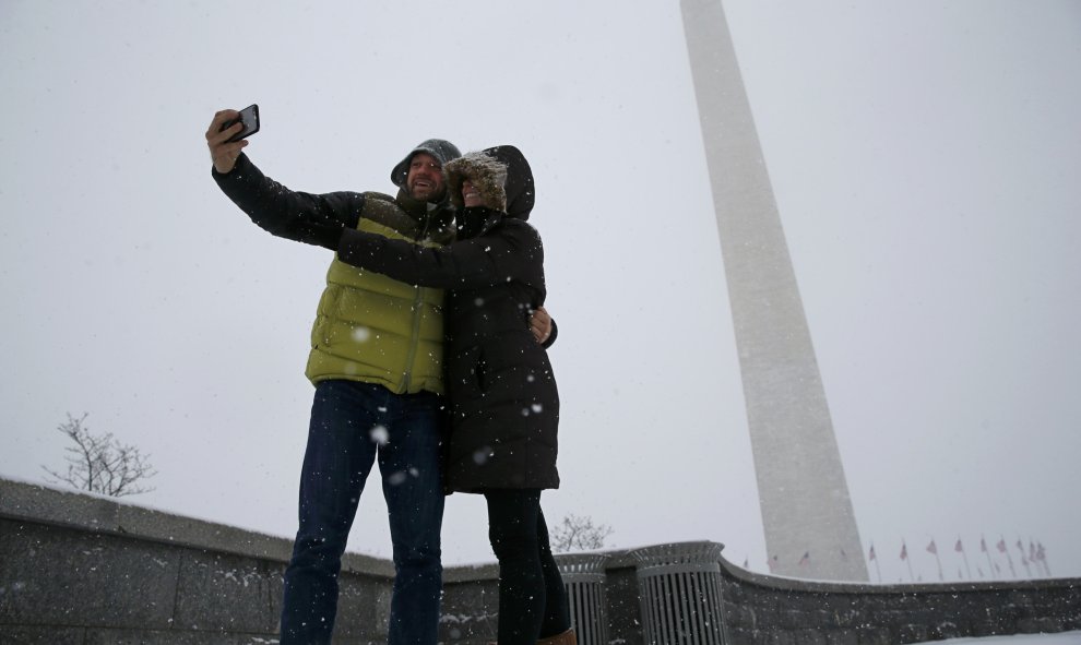 Dos personas se hacen un selfie frente al obelisco de Washington, bajo la nieve. /REUTERS