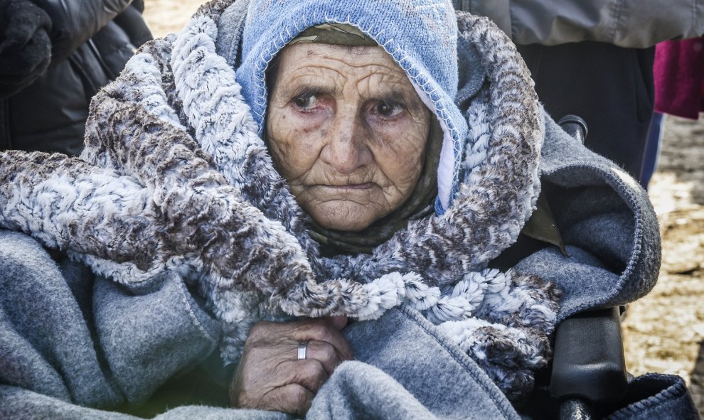 Una anciana en silla de ruedas llega junto con otros emigrantes y refugiados a la aldea de Miratovac después de cruzar a Serbia por la frontera con Macedonia, el 28 de enero de 2016./AFP/ARMEND NIMANI