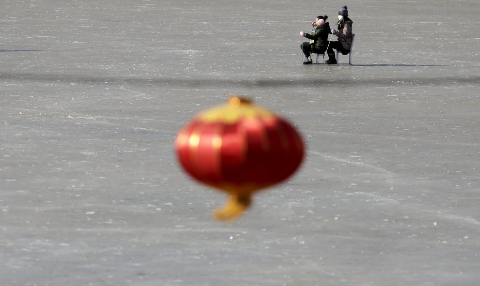 Personas desplazandose en trineos improvisados en un lago congelado en Pekín. REUTERS/Damir Sagolj