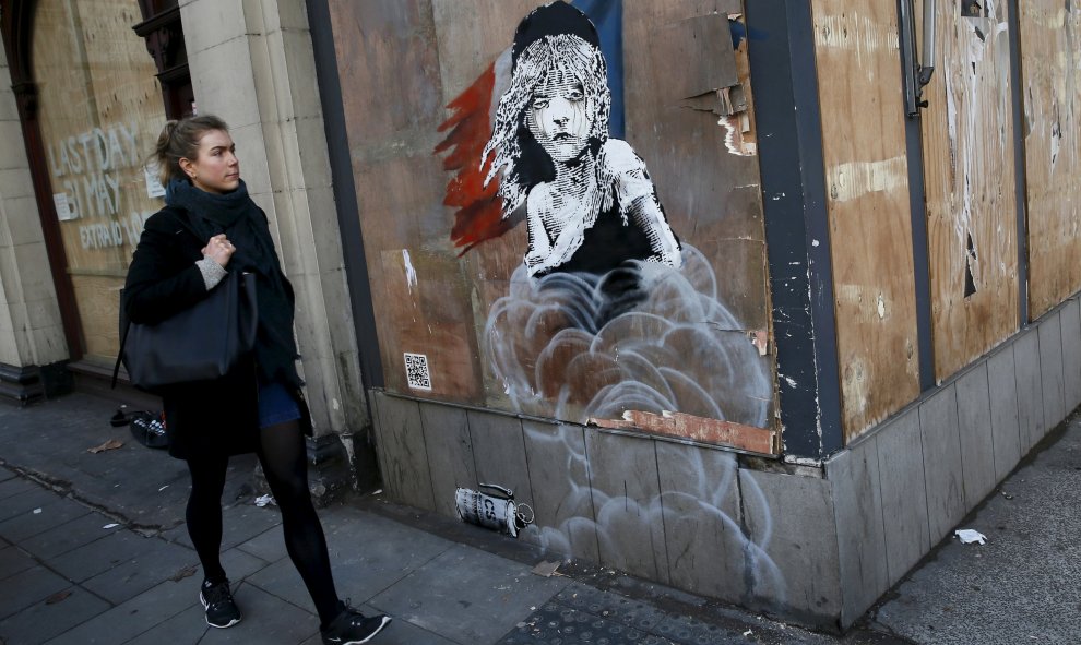 Una mujer pasa junto al nuevo graffiti de Banksy, frente a la embajada francesa en Londres. REUTERS/Stefan Wermuth
