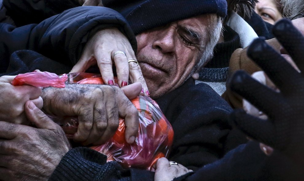 Un hombre agarra una bolsa de mandarinas mientras los agricultores entregan productos gratis, durante una protesta en Atenas. REUTERS/Alkis Konstantinidis