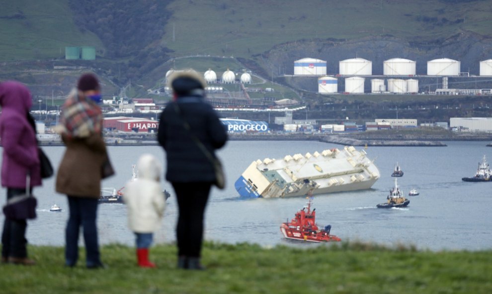 Varias personas observan el carguero "Modern Express", que se encontraba a la deriva en el Golfo de Vizcaya tras sufrir una fuerte escora, entrando remolcado al puerto de Bilbao. El mercante se encuentra desde las 5 de la tarde dentro del puerto y va en