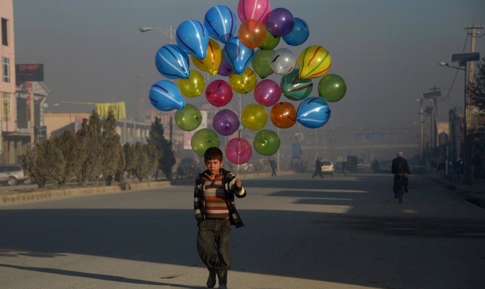 Un niño afgano camina mientras busca clientes que compren sus globos en las calles de Mazar -i- Sharif, el 3 de febrero de 2016. AFP PHOTO / Farshad Usyan