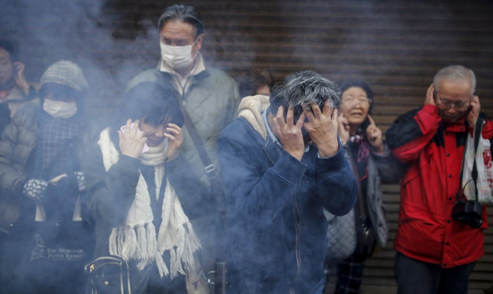 Unos asistentes de la celebración del Año Nuevo del Mono de Fuego Chino se tapan los oídos ante el estruendo ruido de los petardos, en el barrio de Chinatown de Yokohama, al sur de Tokio, Japón. REUTERS/Thomas Peter