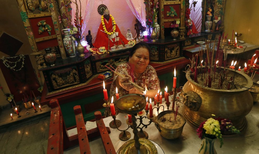 Una mujer de la comunidad china enciende una vela mientras reza en el templo de Calcuta, India. REUTERS/Rupak De Chowdhuri