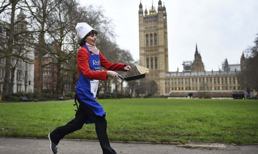 Una parlamentaria corre mientras da la vuelta a una tortita por los jardines de Victoria junto a las Casas del Parlamento en Londres, durante la tradicional carrera de tortitas para recaudar dinero para obras de caridad. EFE/Andy Rain
