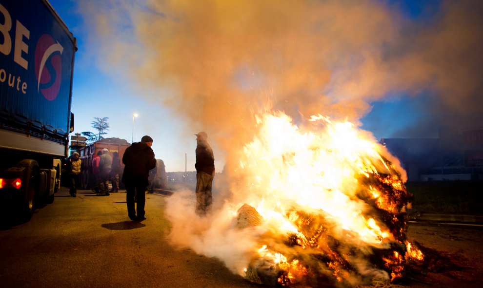 Los manifestantes usan tractores y queman neumáticos cerca de la autopista RN 165 para bloquear el acceso por carretera a Vannes, al oeste de Francia, el 15 de febrero de 2016, durante una protesta contra la caída de los precios de los productos lácteos y