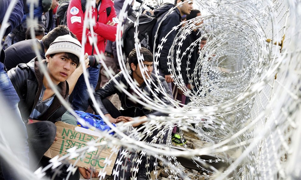 Refugiados permanecen junto al alambre de púas colocado en la frontera entre Grecia y Macedonia, cerca de Gevgelija. EFE/Nake Batev