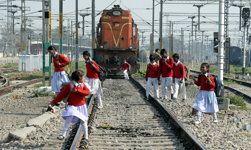 Estudiantes indios cruzan las vías del tren para ir a casa después de clase en la estación de trenes de la ciudad de Jalandhar./ AFP/ Shammi MEHRA