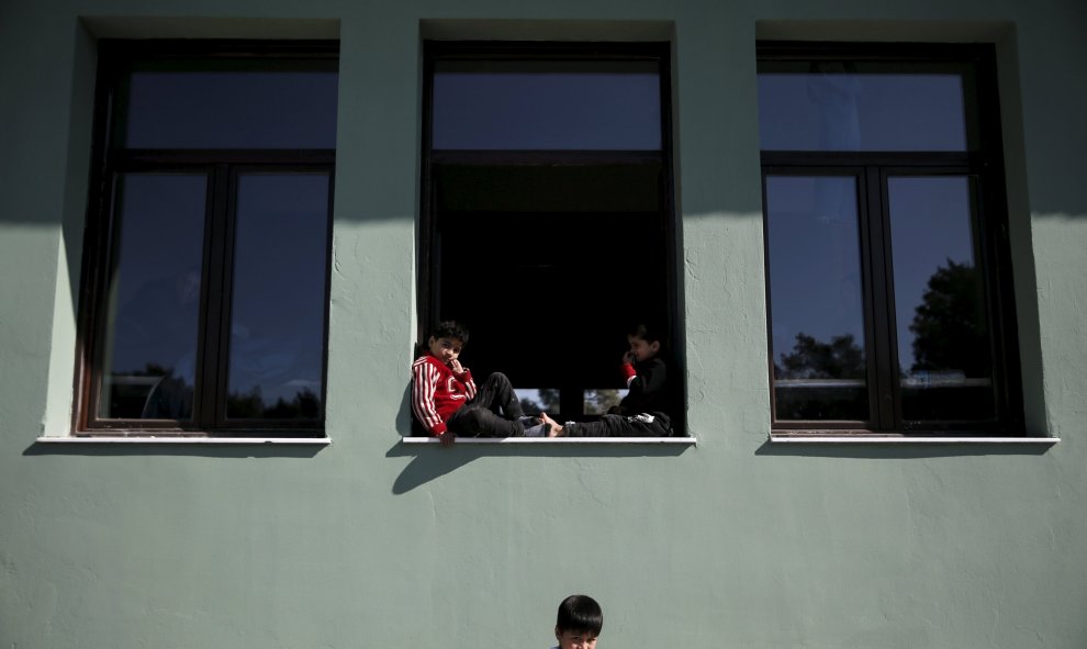 Los niños se sientan en una ventana de un edificio utilizado como dormitorio en un campo de refugiados e inmigrantes en Schisto, cerca de Atenas, Grecia, 25 de febrero de 2016. REUTERS / Alkis Konstantinidis