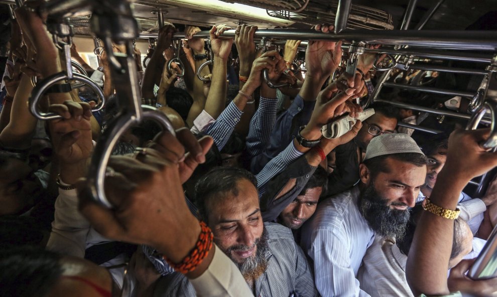 Varios trabajadores viajan hacinados en un tren en la estación de Bombay, India. EFE/Divyakant Solanki