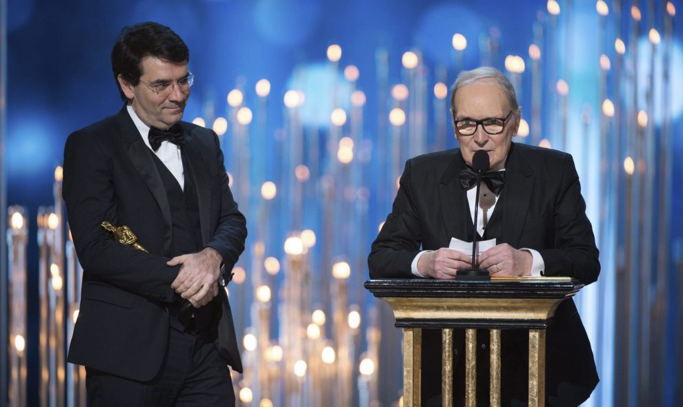 El maestro italiano Ennio Morricone (d) recoge su Óscar a la mejor banda sonora por "The Hateful Eight" (Los Odiosos Ocho) durante la 88ª edición de la ceremonia de los Óscar celebrada la noche de ayer, 28 de febrero de 2016, en el Teatro Dolby de Hollywo