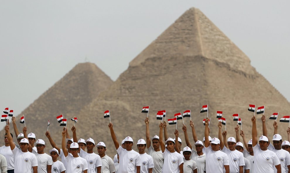 Los estudiantes de la Academia Militar egipcia sostienen banderas egipcias en la apertura del Campeonato Internacional de Paracaidismo, que está organizado por la Federación de Deportes Aéreos Egipcios (EPAF), frente a las grandes pirámides de Giza, Egipt