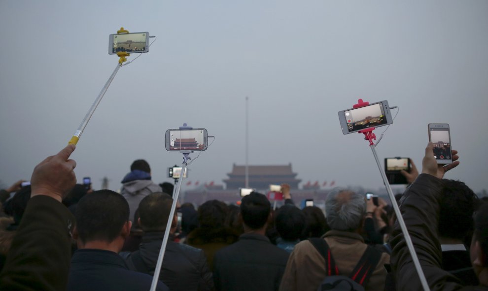 Personas levantan sus teléfonos móviles y cámaras para grabar y tomar fotografías de la ceremonia de izamiento de bandera en la Plaza de Tiananmen en Pekín. REUTERS/Damir Sagolj