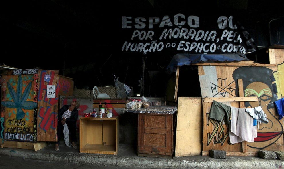 Una mujer se sienta delante de su casa, construida bajo un puente en el centro de Sao Paulo. REUTERS/Paulo Whitaker