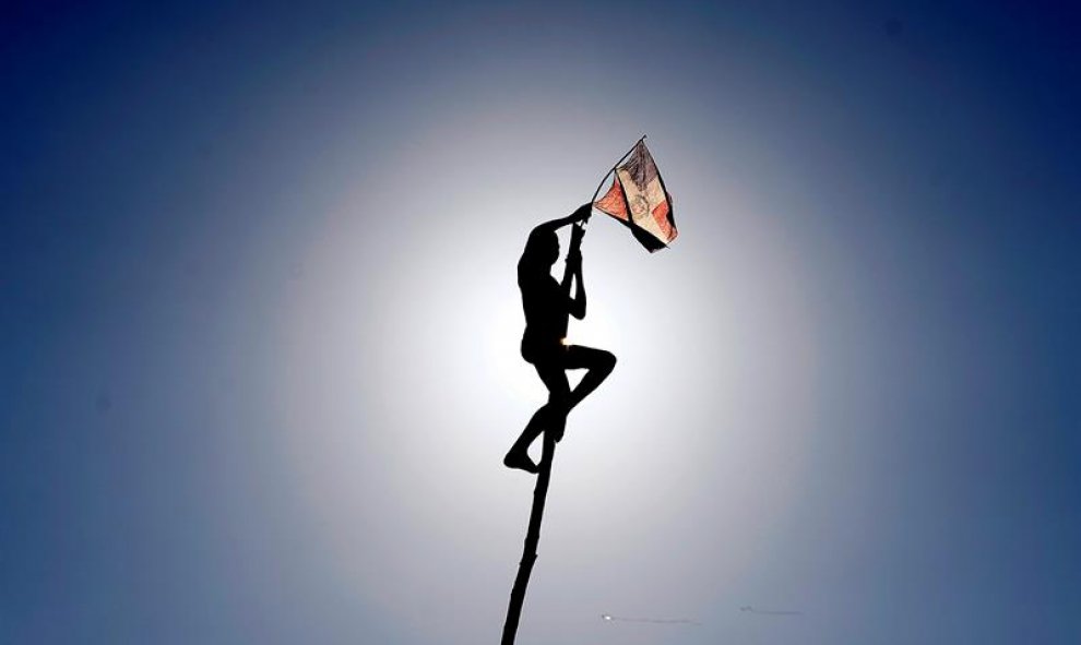 Un niño iza una bandera tras escalar un palo de unos ocho metros de altura durante la celebración del Desfile Nacional de Carnaval en Santo Domingo (República Dominicana). EFE/Orlando Barría