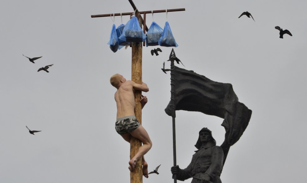 Un hombre intenta subir un poste de madera para obtener un premio durante las celebraciones de Maslenitsa en Vladivostok. REUTERS/Yuri Maltsev
