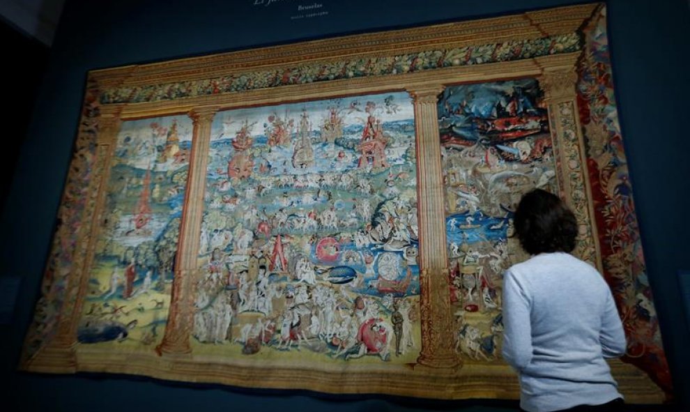 Una mujer objserva un tapiz con la obra 'El jardín de las Delicias' durante la presentación de la exposición 'El Bosco en El Escorial. Celebración del V Centenario', que muestra en el Monasterio de El Escorial once piezas dela rtista pertenecientes a Patr