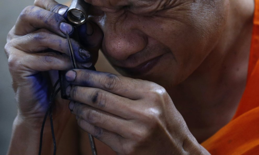 Un monje budista prepara sus herramientas antes de tatuar el cuerpo de un hombre en Bangkok. REUTERS/Chaiwat Subprasom
