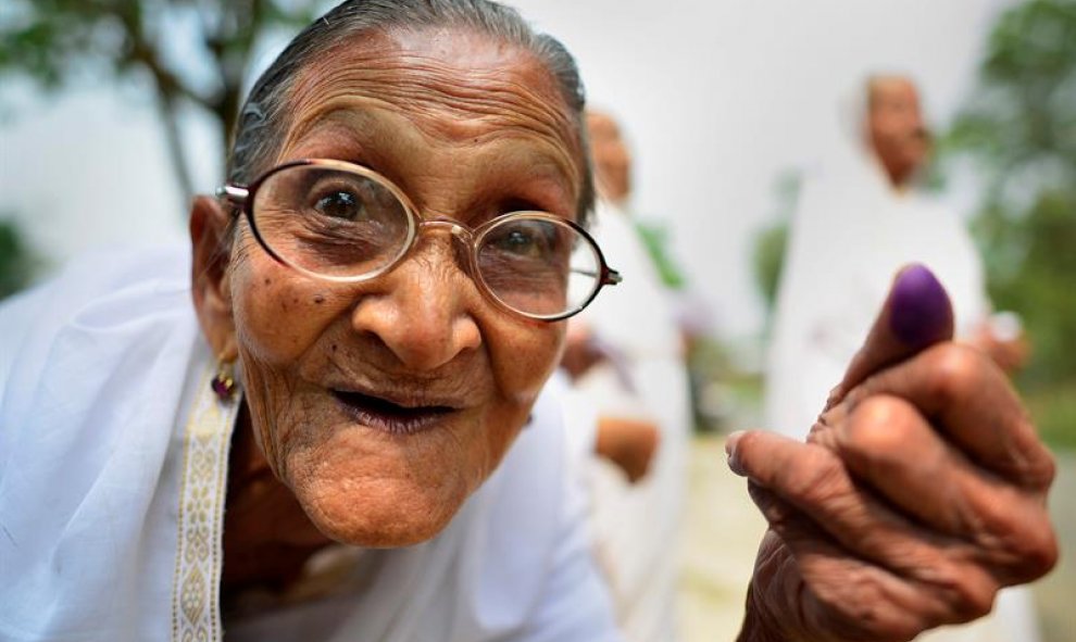 Una anciana india muestra su dedo marcado con tinta tras votar en la primera fase de las elecciones a la Asamblea de Assam, en el distrito de Jorhat, dentro del estado indio de Assam. EFE/Str