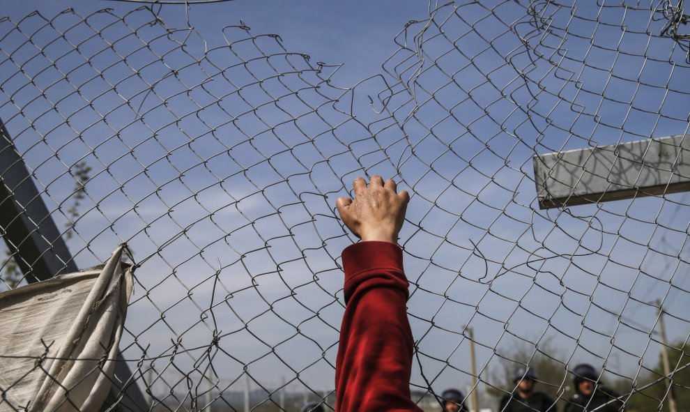 Un migrante intenta abrir una valla de la frontera en un campamento improvisado en la frontera entre Grecia y Macedonia, cerca de la localidad de Idomeni. REUTERS/Marko Djurica