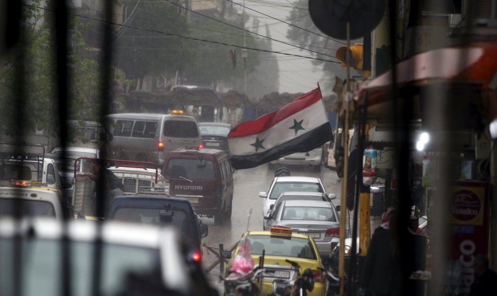 Una bandera siria ondea en una abarrotada calle comercial de Qamishli. /REUTERS-Rodi Said