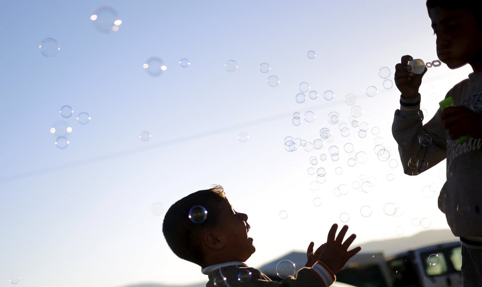 Niños juegan con burbujas de jabón en un campamento improvisado para refugiados en la frontera entre Grecia y Macedonia, cerca de la localidad de Idomeni. REUTERS/Stoyan Nenov