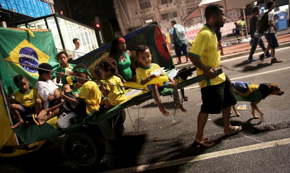 Un hombre carga con seis niños y una mujer, todos vestidos con la camiseta de la selección nacional de fútbol de Brasil, durante las protestas contra Dilma Rousseff. REUTERS/Nacho Doce