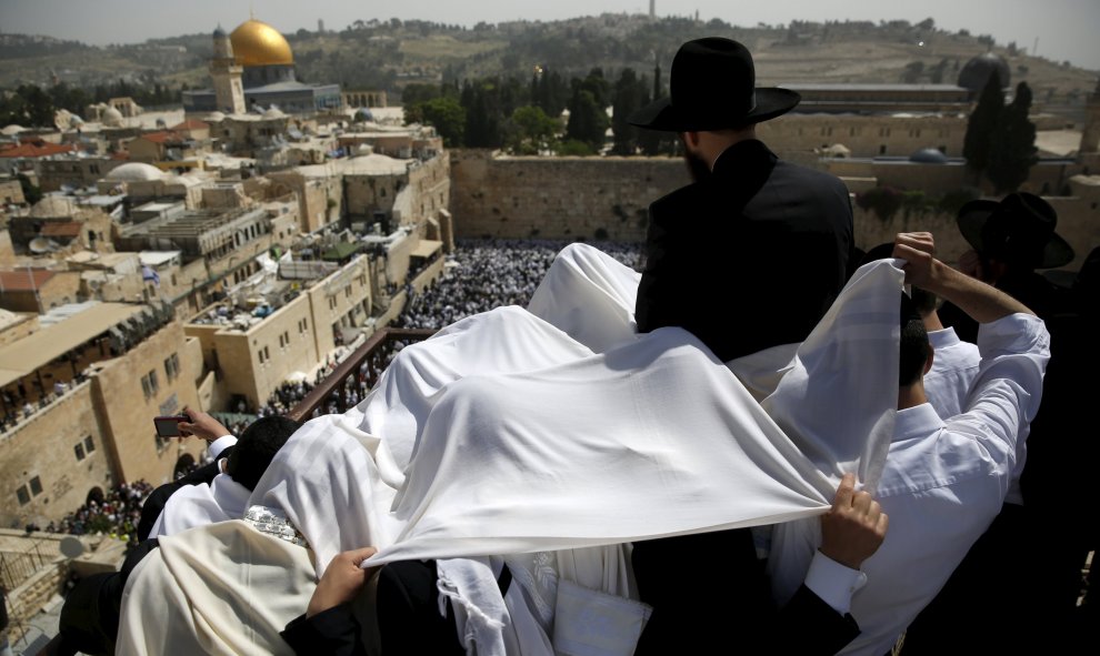 Unos fieles judíos se cubren cpn unas mantas para orar en la azotea con vistas al Muro Occidental durante una bendición sacerdotal especial para la Pascua en la Ciudad Vieja de Jerusalén. REUTERS/Ronen Zvulun