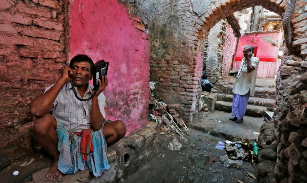 Trabajadores hablan con teléfonos inalámbricos en un callejón en Calcuta. REUTERS/Rupak De Chowdhuri