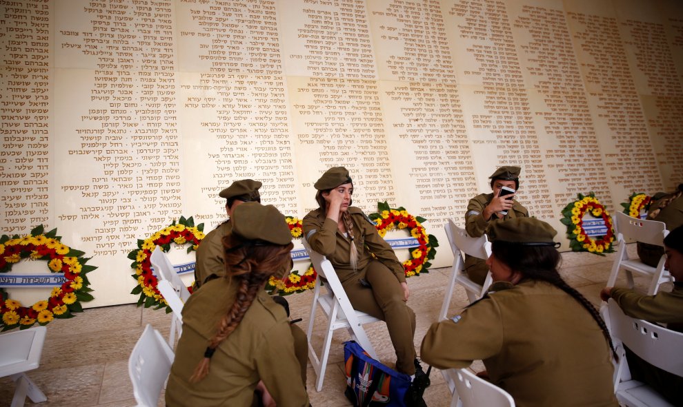 Soldadas israelíes sentados frente a un monumento grabado con los nombres de soldados israelíes, mientras esperan el inicio  de la ceremonia del Día Memorial en Jerusalén, Israel. REUTERS/Ronen Zvulun