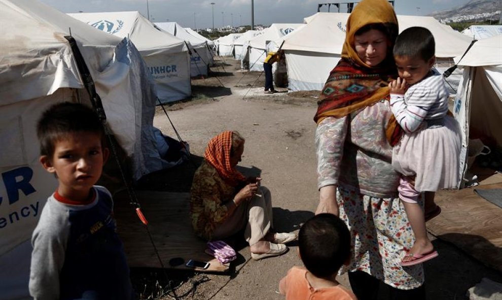 Refugiados, frente a su tienda de campaña en el antiguo Complejo Olímpico Helliniko, donde más de 1.000 refugiados se alojan, en Atenas, Grecia. EFE/Yannis Kolesidis